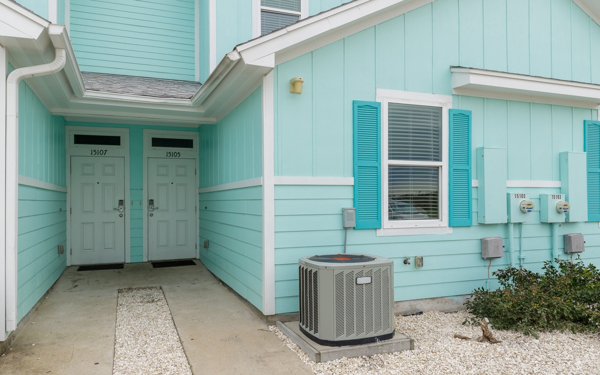 Charming turquoise beach-style building with numbered units and coastal-inspired shutters creates a welcoming arrival experience.