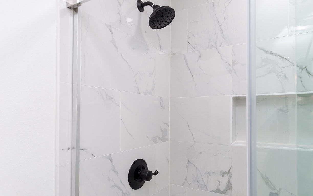 Step into your luxurious marble shower with elegant black fixtures and convenient built-in storage niches for all your essentials.