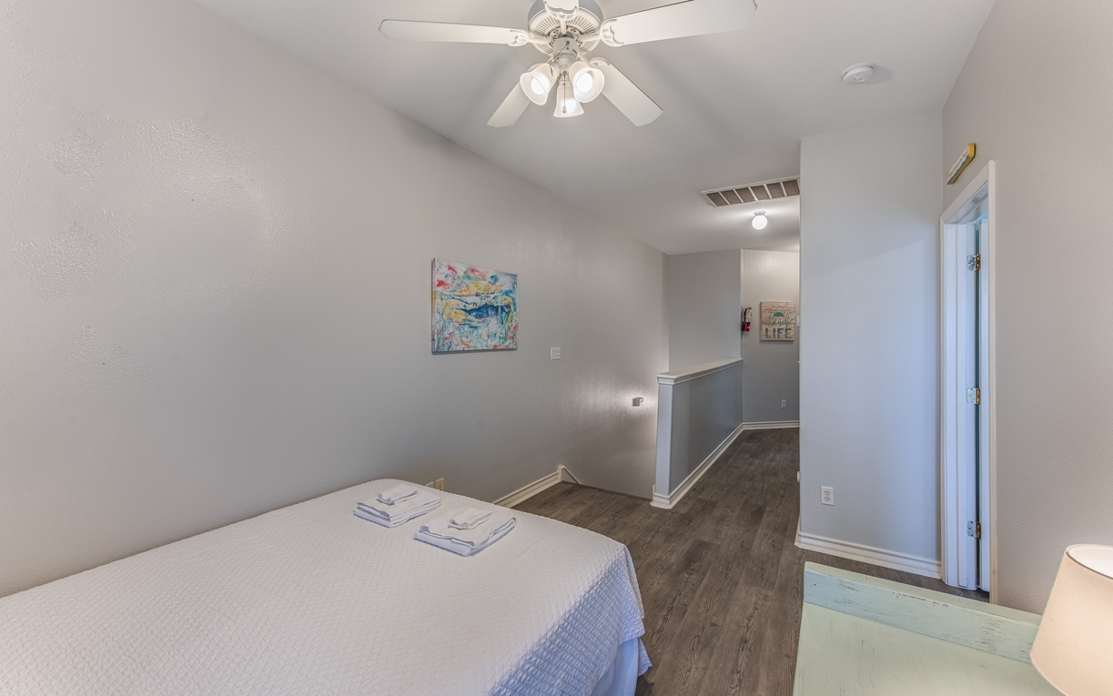 Your serene bedroom features a comfortable bed with fresh towels, ceiling fan for optimal comfort, and modern hardwood floors.