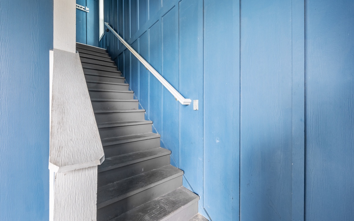 Climb the charming blue staircase with its crisp white handrail, leading you to your peaceful retreat above.