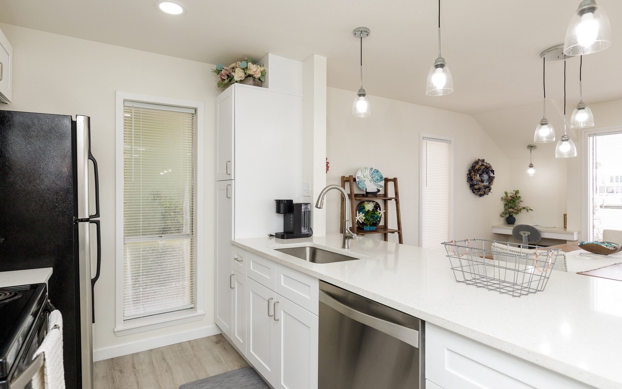 Your bright, modern kitchen awaits with gleaming white counters, stylish pendant lighting, and everything needed for memorable meals.