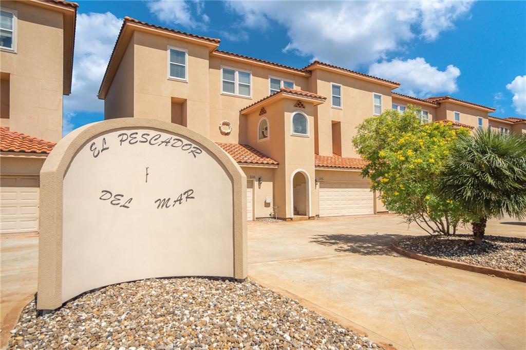 Welcoming entrance to El Pescador Del Mar, where Mediterranean-style architecture meets tropical paradise under brilliant blue skies.
