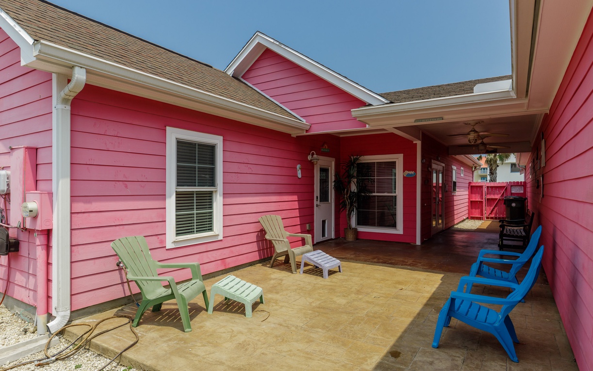 Vibrant pink cottage with colorful patio seating for relaxing under the coastal sky.