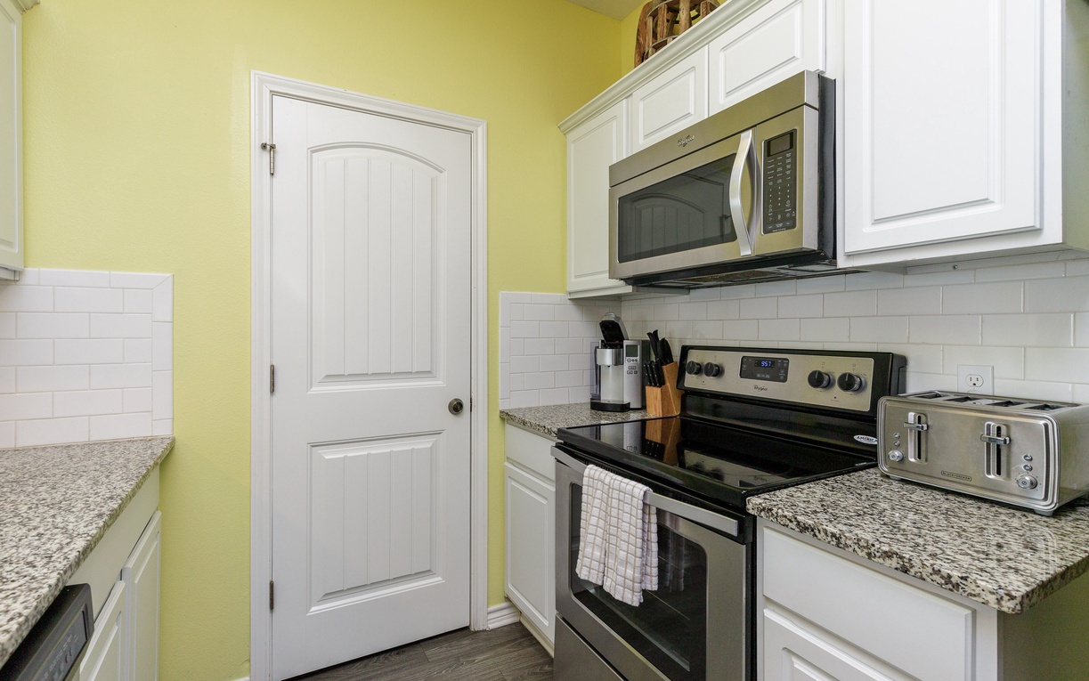 Your bright, cheerful kitchen awaits with sunny yellow walls and granite countertops, fully equipped for memorable meals together.