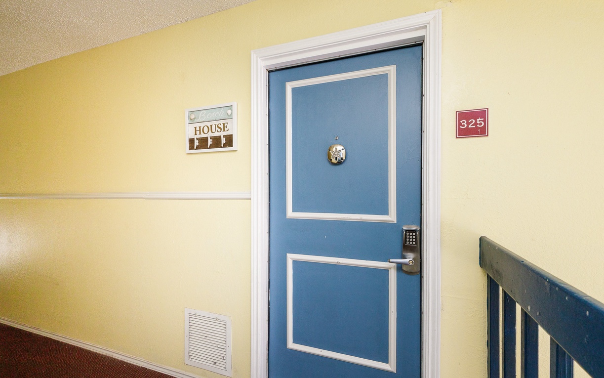 Your charming blue door awaits in this well-maintained hallway with clear room signage and secure keypad entry.