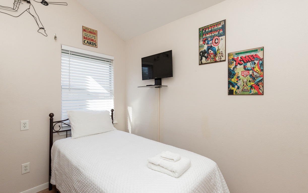 Your cozy single bedroom features crisp linens, vintage comic art, and a wall-mounted TV for your entertainment.