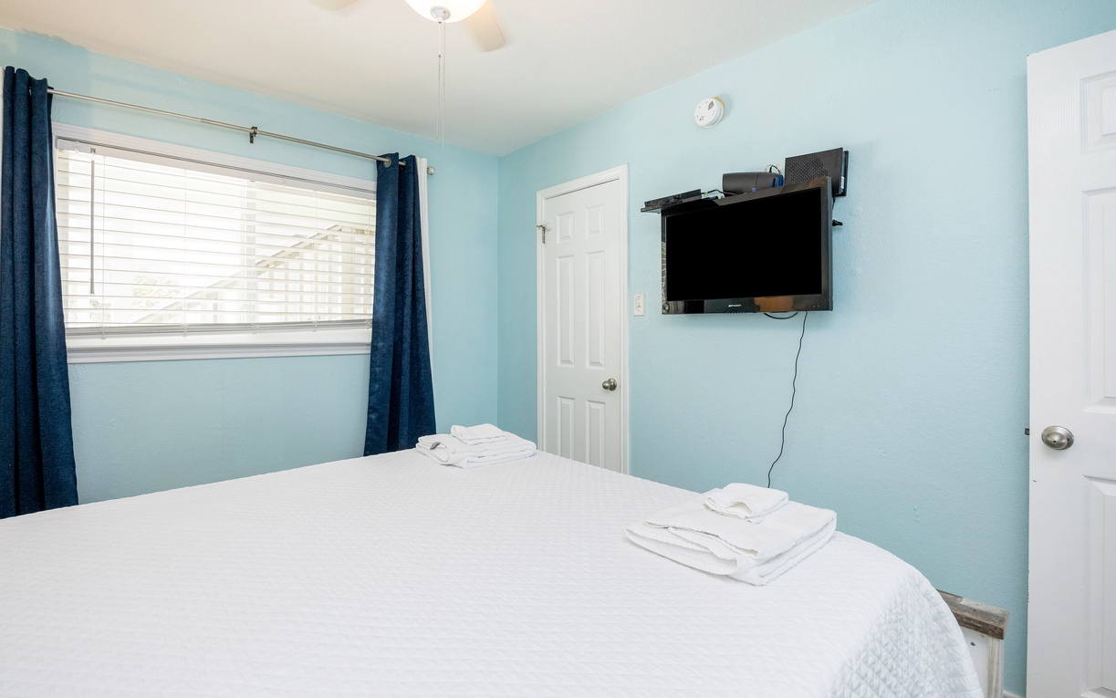 Unwind in your peaceful bedroom with calming blue walls, crisp white linens, and a queen size bed.