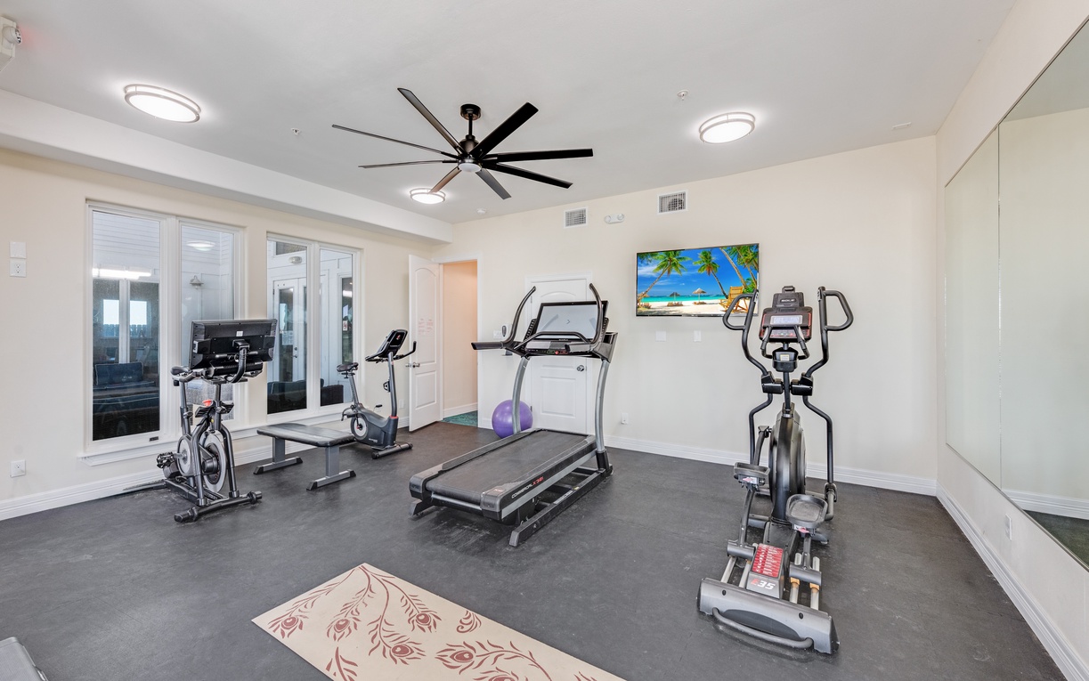 Community fitness suite awaits with premium cardio equipment and tropical beach artwork to inspire your workout routine.