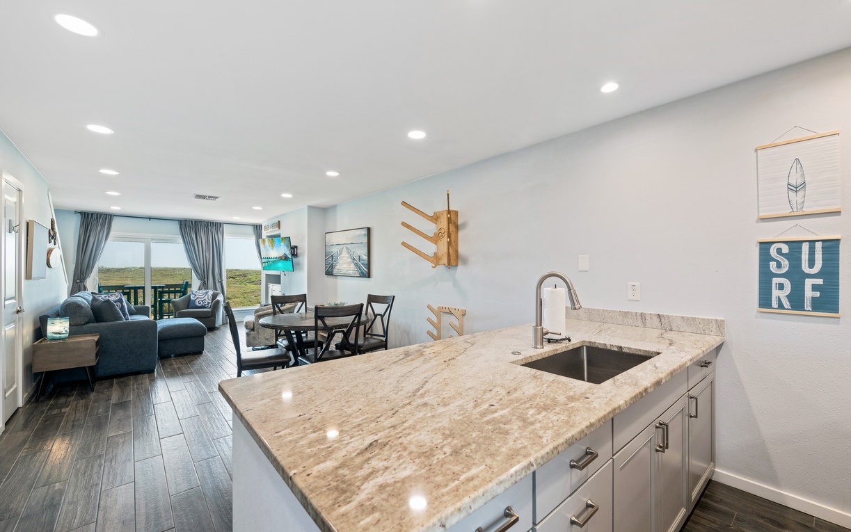 Step into your bright, open coastal retreat where the kitchen flows seamlessly into your living and dining spaces. Natural light floods through to reveal distant dunes framed by windows, inviting you to unwind and embrace the relaxed beach lifestyle.