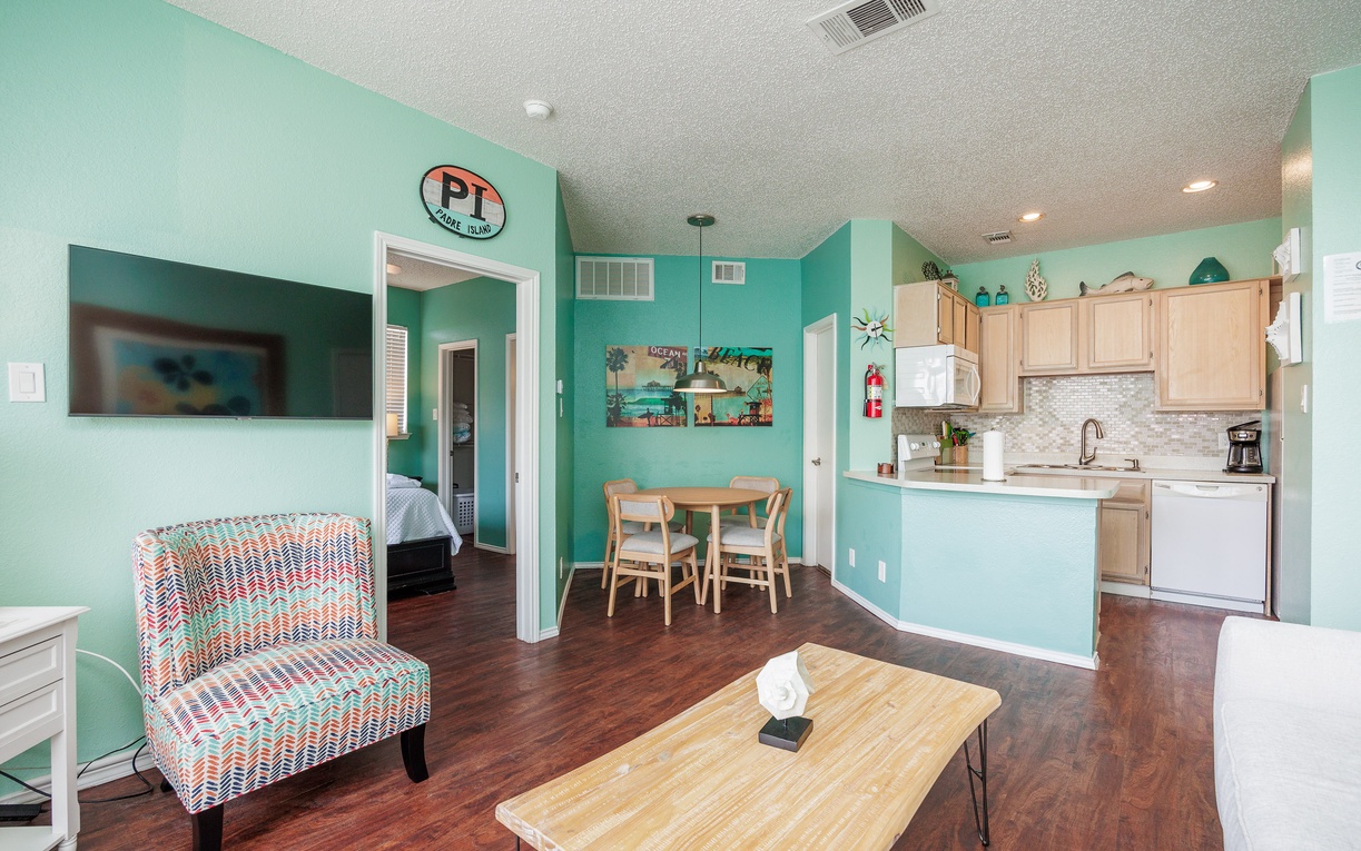Relax in your cheerful open-plan living space with vibrant turquoise walls, modern kitchen, and coastal charm throughout.