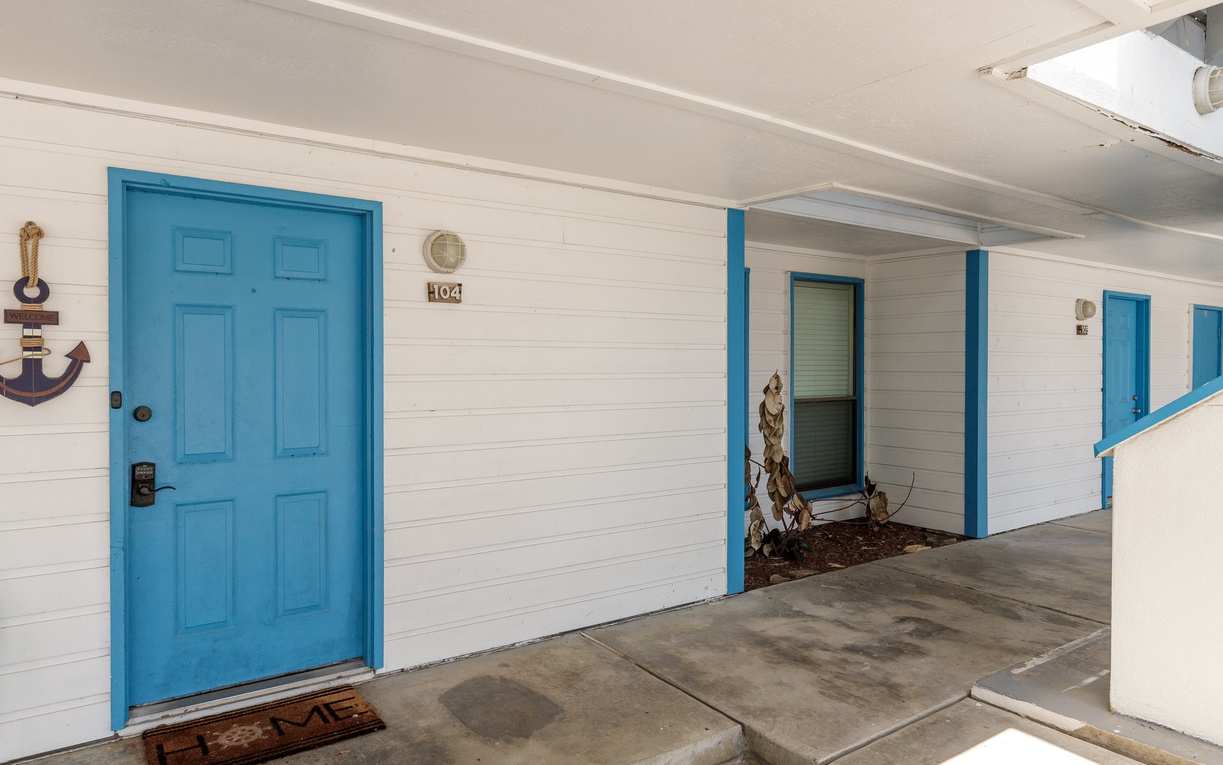 Property exterior features white siding with bright turquoise doors and trim, creating a cheerful coastal-style entrance to the accommodations.