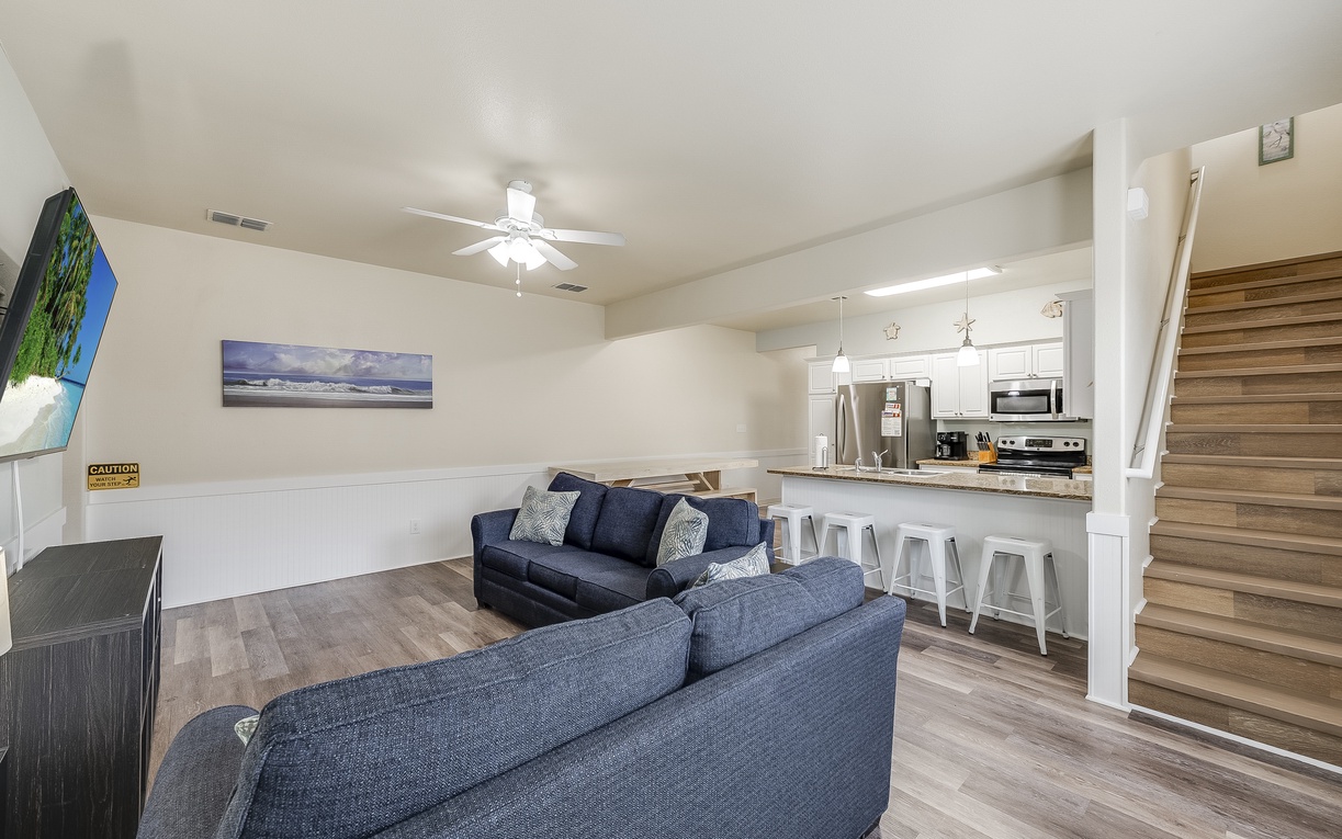 Relax in your open-concept space with plush seating, modern kitchen, and stylish coastal artwork creating the perfect home base.