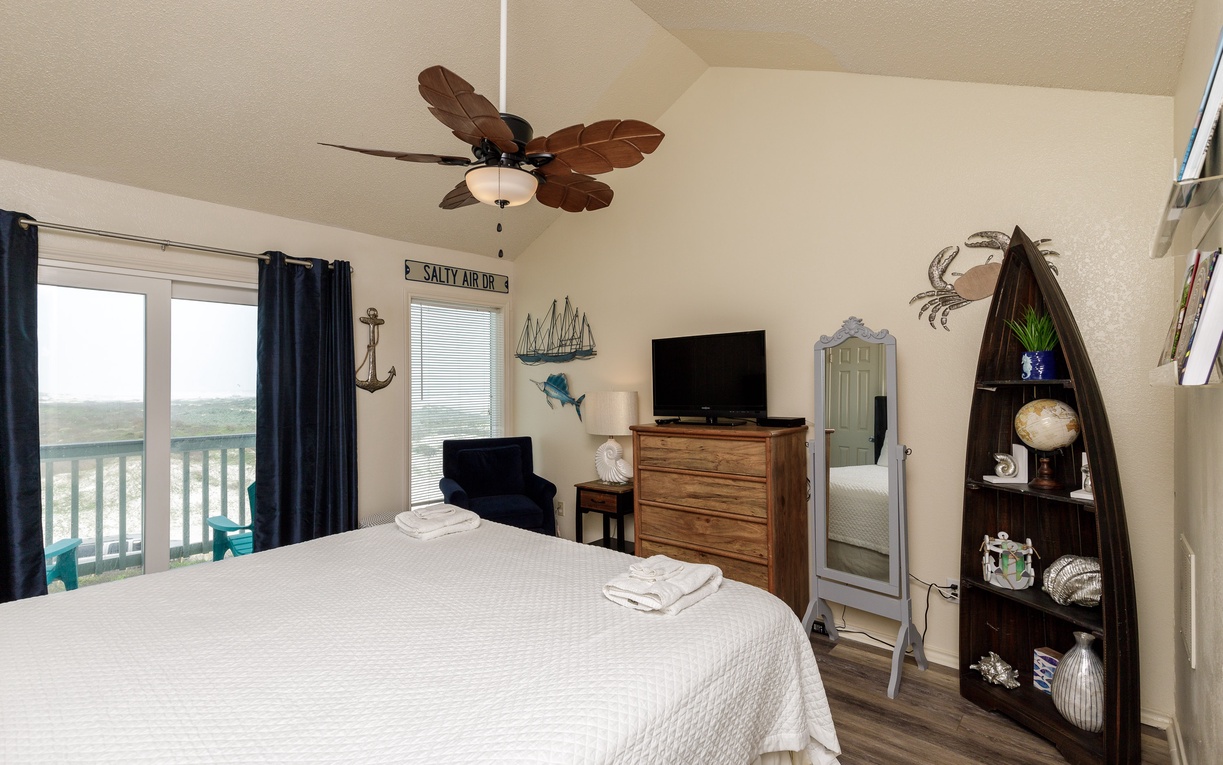 Second floor primary bedroom with king size bed, private bathroom, and private balcony with a view of the beach