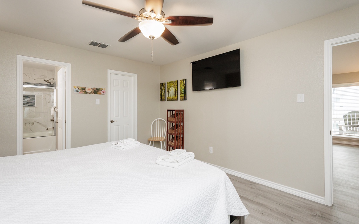 Unwind in your serene bedroom with crisp linens, ceiling fan, and entertainment center for the perfect night's rest.