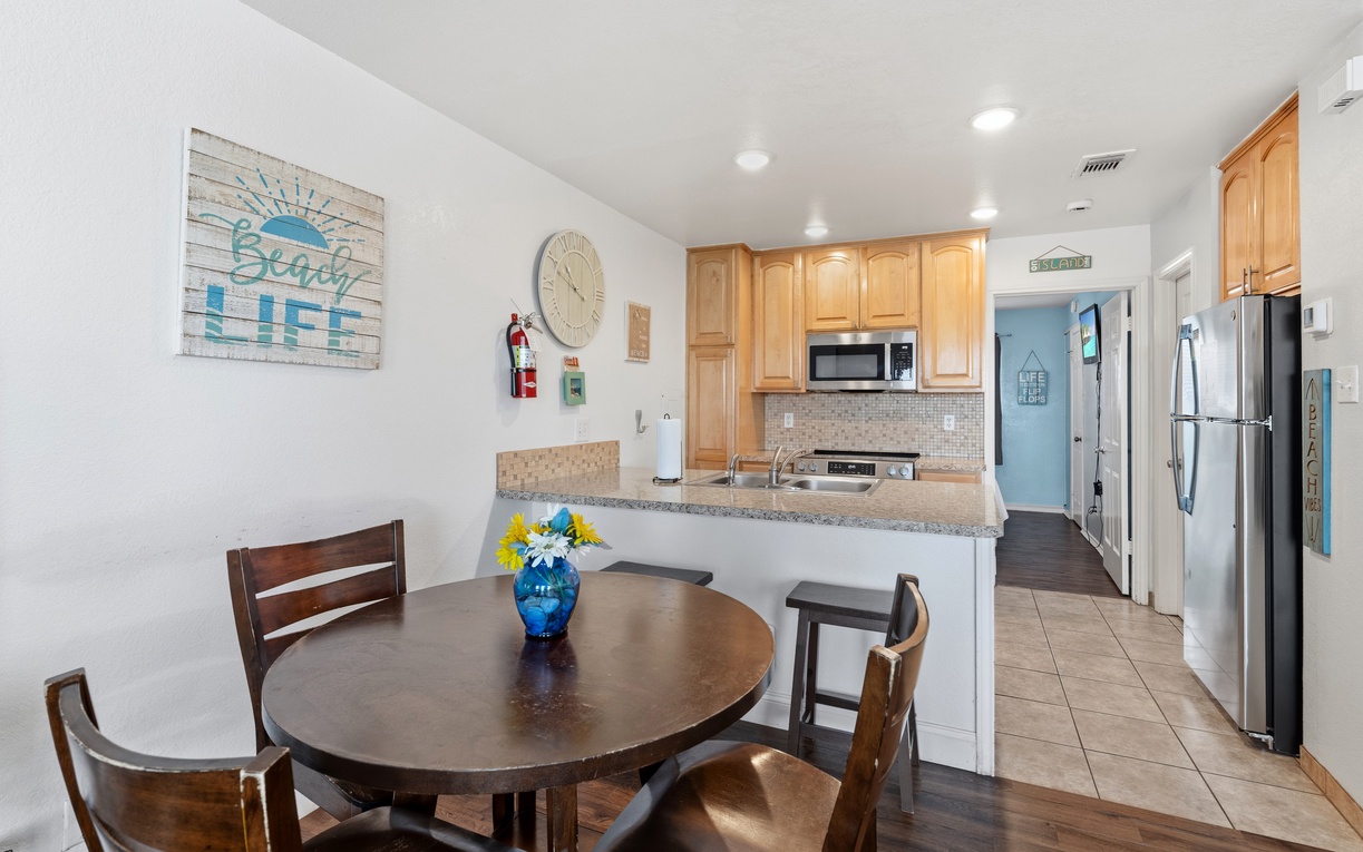 Your open dining and kitchen area welcomes you with coastal charm—enjoy meals at the round table, then whip up fresh snacks in your granite-topped kitchen equipped with stainless appliances.