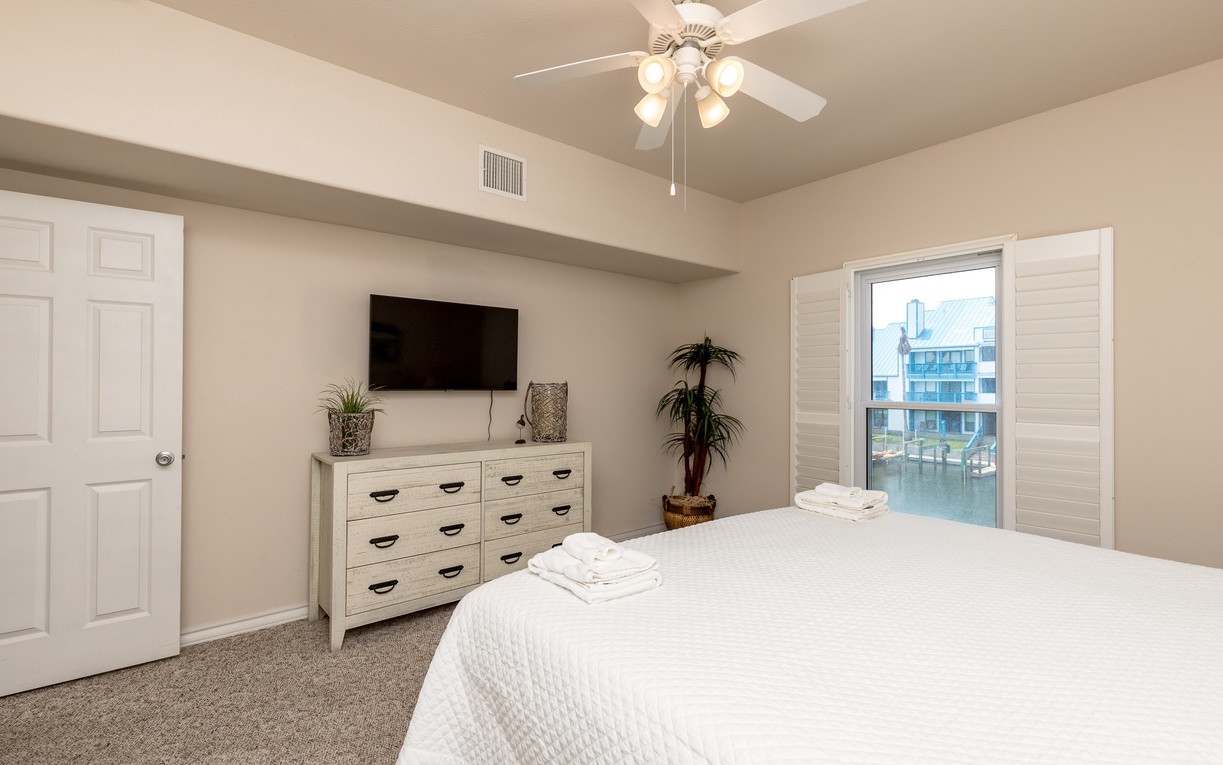 Drift off in your serene bedroom with waterfront views, plush linens, and a ceiling fan keeping you cool.