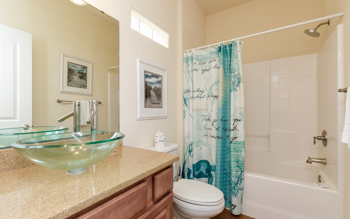 Refresh in your stylish bathroom featuring a unique glass vessel sink, warm granite counters, and coastal-themed decor that creates a spa-like retreat.