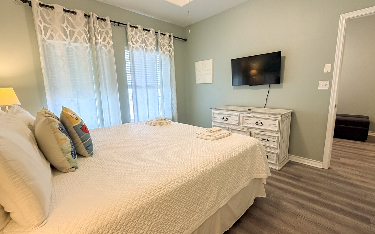 Wake up in your peaceful bedroom featuring soft coastal hues and abundant natural light streaming through windows.