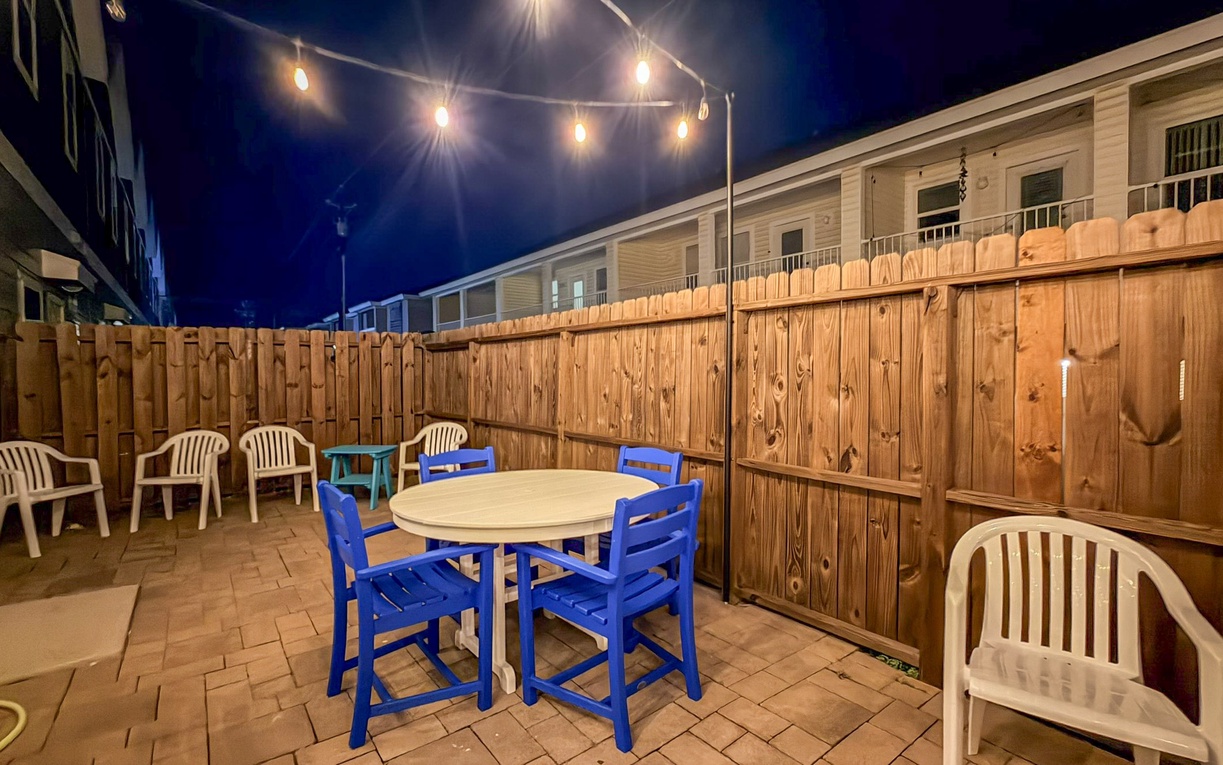 Your private patio glows under warm string lights, creating the perfect evening atmosphere for outdoor dining and relaxation.