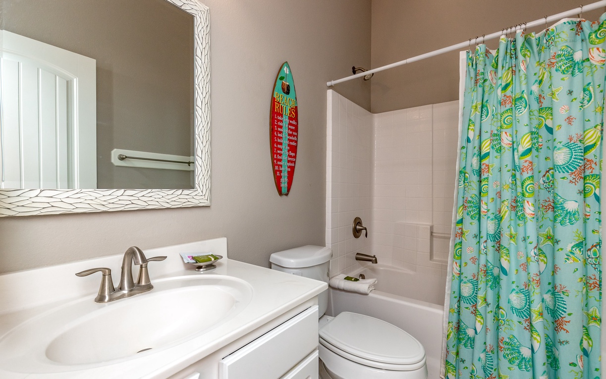 Freshen up in your coastal-themed bathroom, featuring tropical touches and a charming surfboard accent that sets the perfect beach vacation mood.