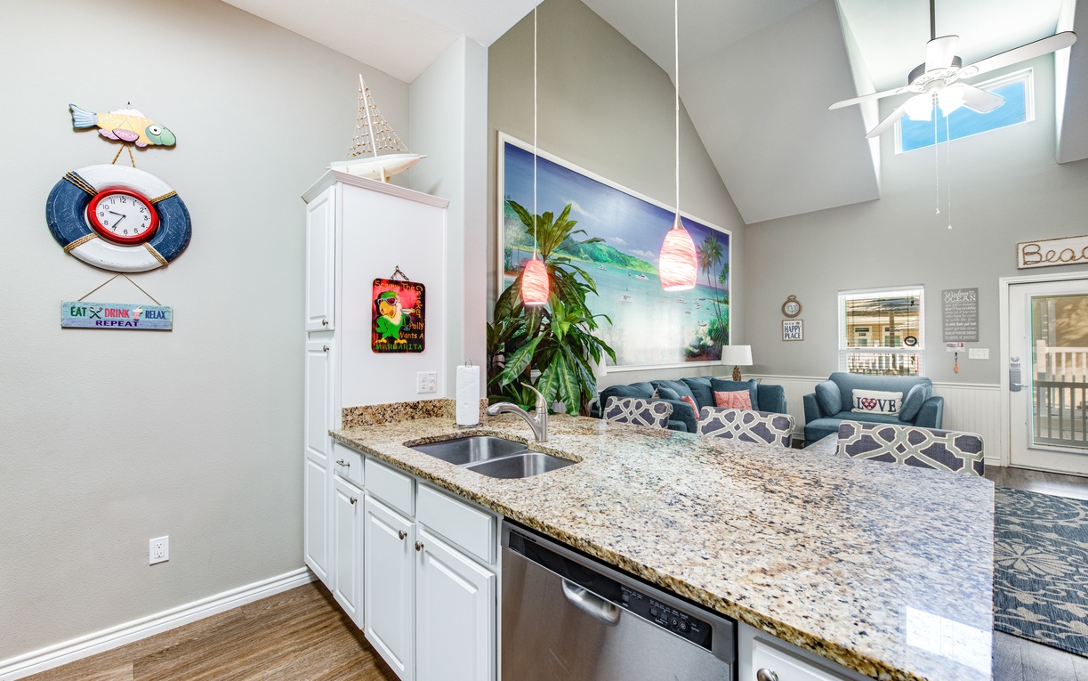 Your bright kitchen features granite counters and stainless appliances, flowing into a cozy living area with tropical artwork and skylights.