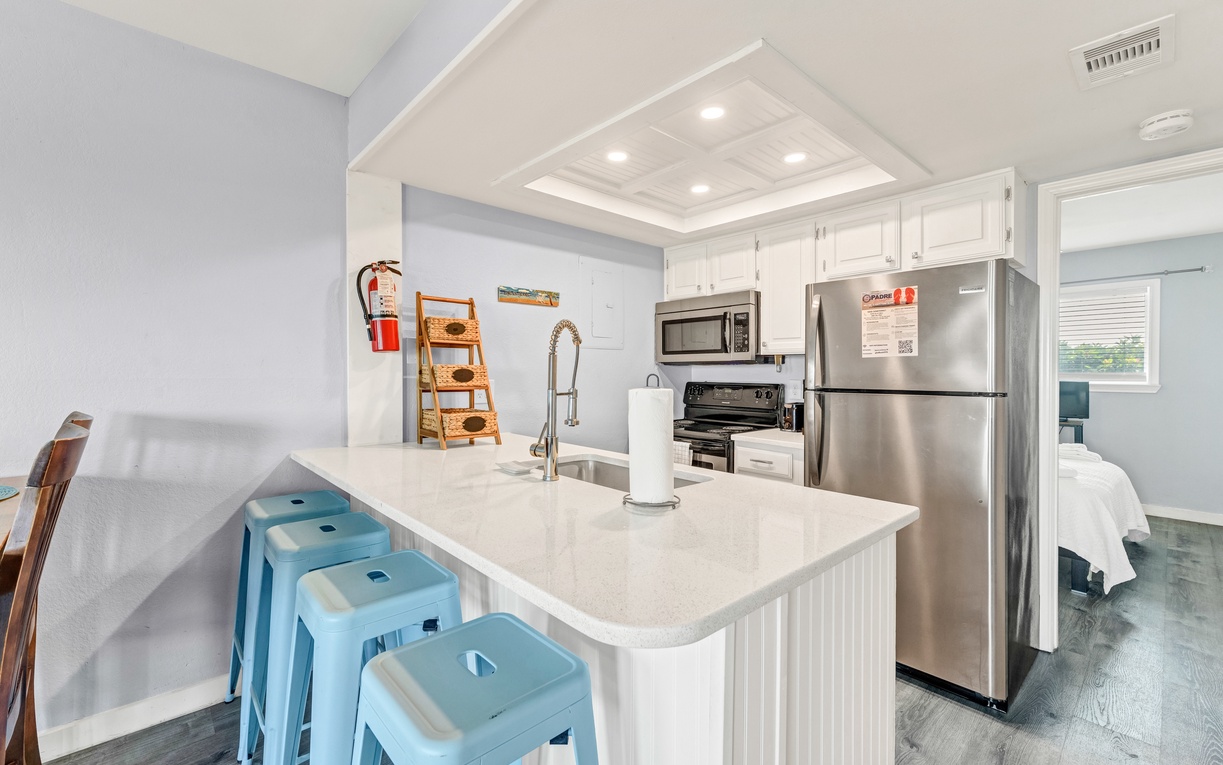 Your bright kitchen features modern stainless appliances, marble countertops, and cheerful blue stools perfect for morning coffee or casual meals.