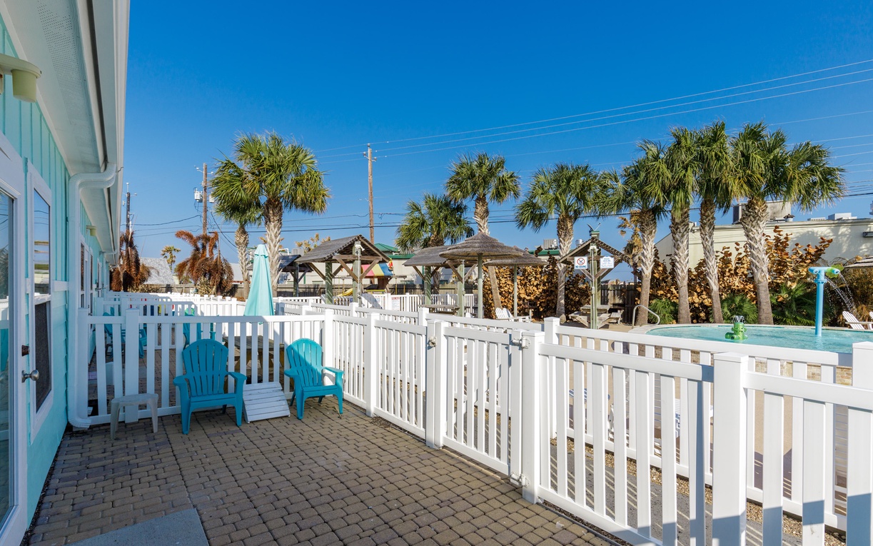 Relax on your private patio with turquoise Adirondack chairs, enjoying tropical palm views under endless blue skies.