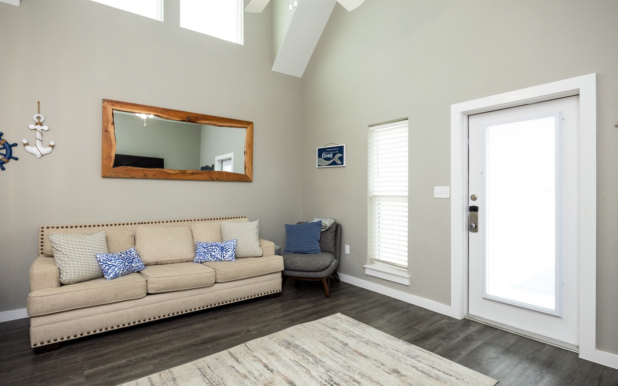 Relax in this bright living room with vaulted ceilings, cozy seating, and cheerful nautical touches that create your perfect coastal retreat.