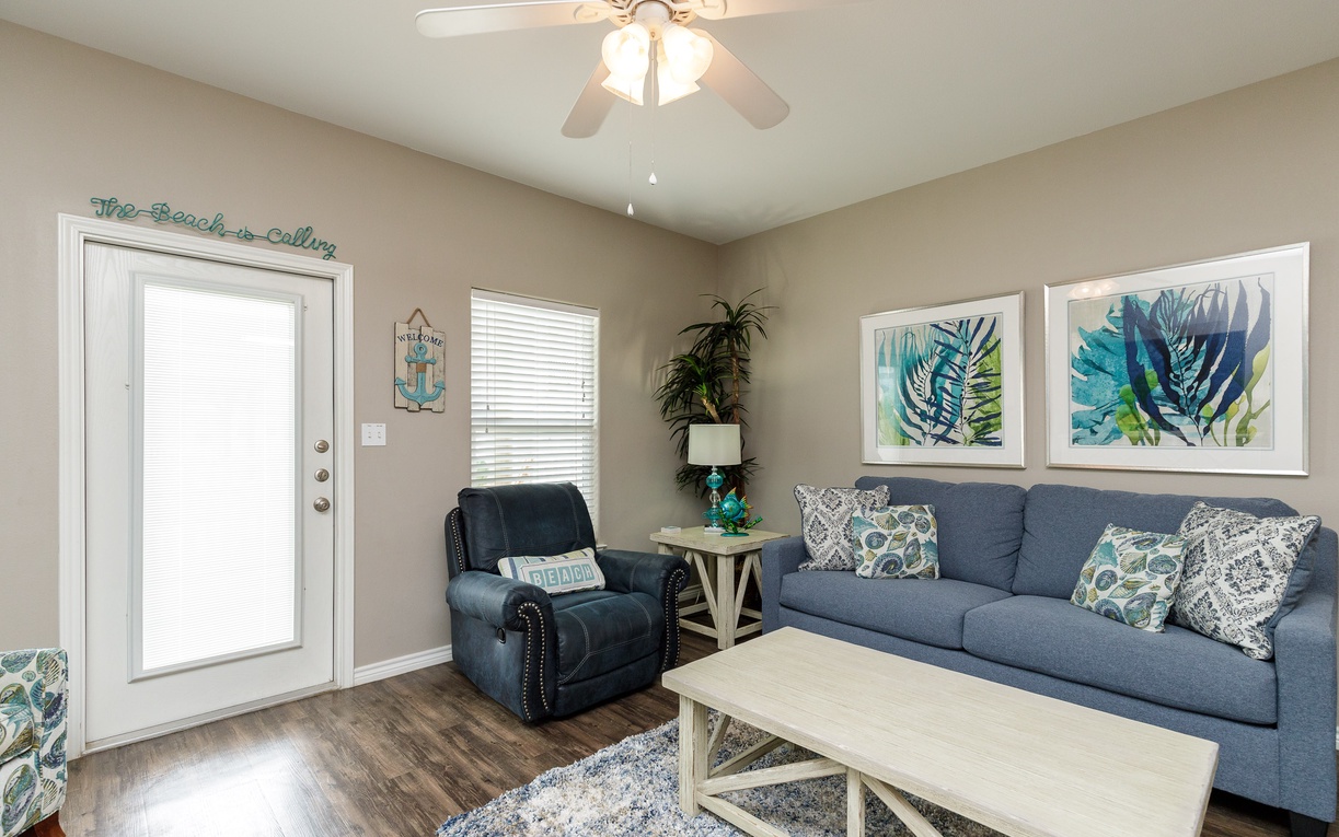 Relax in your coastal-themed living room with plush seating, tropical artwork, and that perfect vacation vibe welcoming you home.