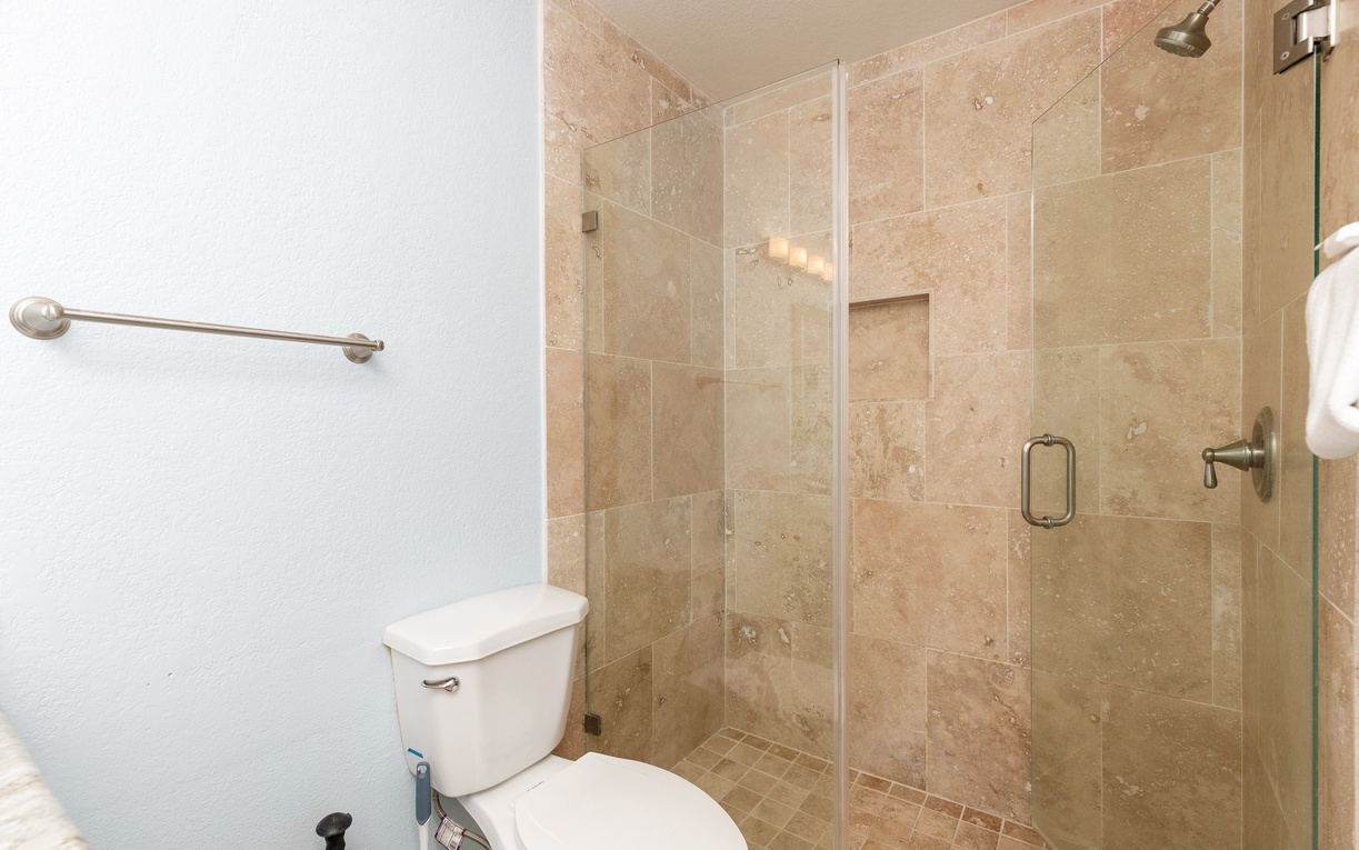 Refresh in your elegant bathroom featuring a spacious glass-enclosed shower with beautiful travertine tiles and modern fixtures.