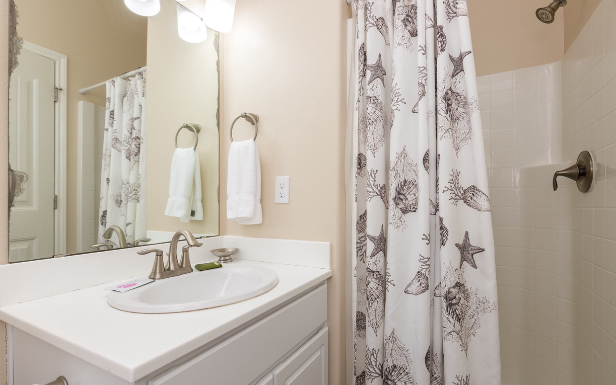 Refresh in your private bathroom featuring coastal-themed touches and fresh white linens that welcome you after beach days.