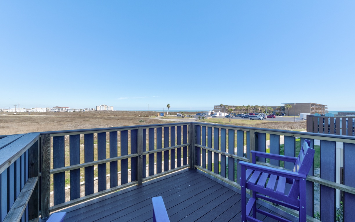 Expansive coastal deck with comfortable seating overlooking open landscape and distant oceanfront development.