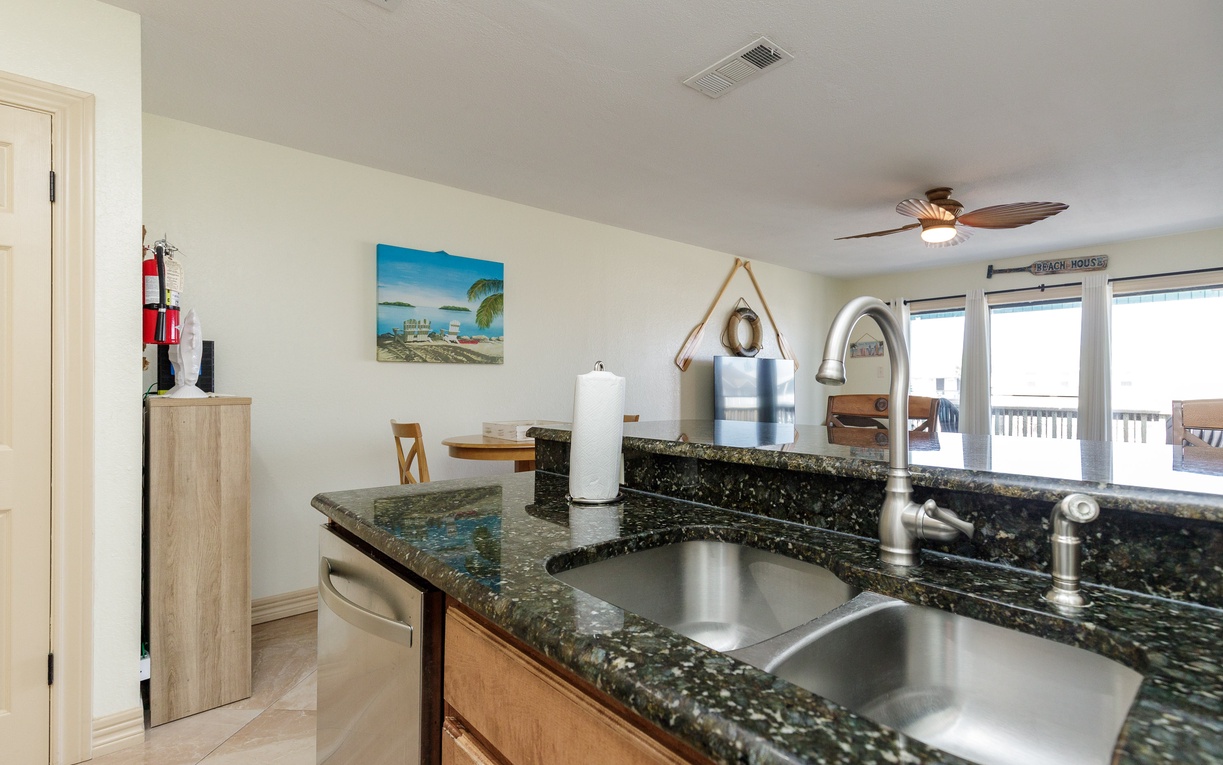 Your kitchen features granite countertops and stainless steel sink, perfect for preparing meals while enjoying ocean views through the windows.