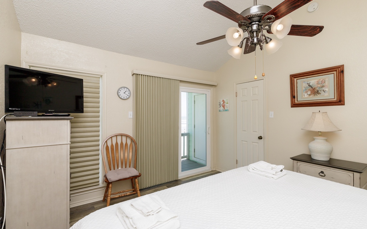Unwind in your cozy bedroom with comfortable bedding, ceiling fan, flat-screen TV, and charming coastal touches that create the perfect retreat.