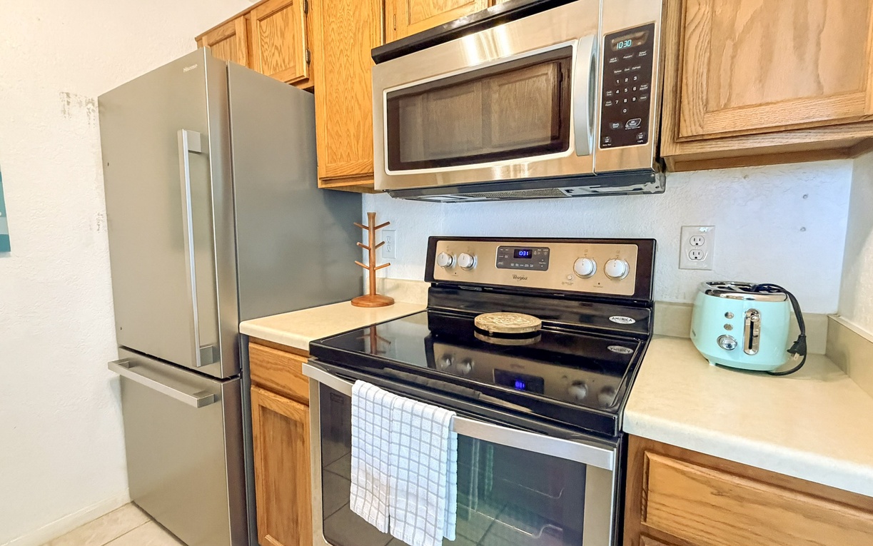 Your fully equipped kitchen awaits with stainless steel appliances, warm wood cabinets, and that charming mint toaster ready for morning treats.