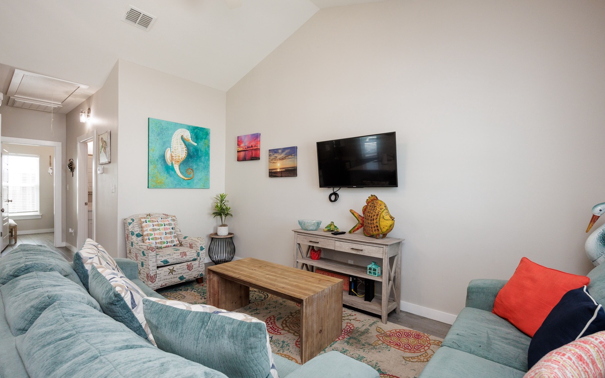 Relax in your coastal-inspired living space with plush seating, vibrant seahorse art, and entertainment center perfect for unwinding after beach days.