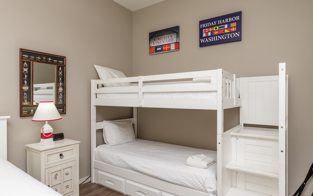 Your kids will love this cozy bunk bed setup, complete with nautical artwork and a bedside lamp for bedtime stories.