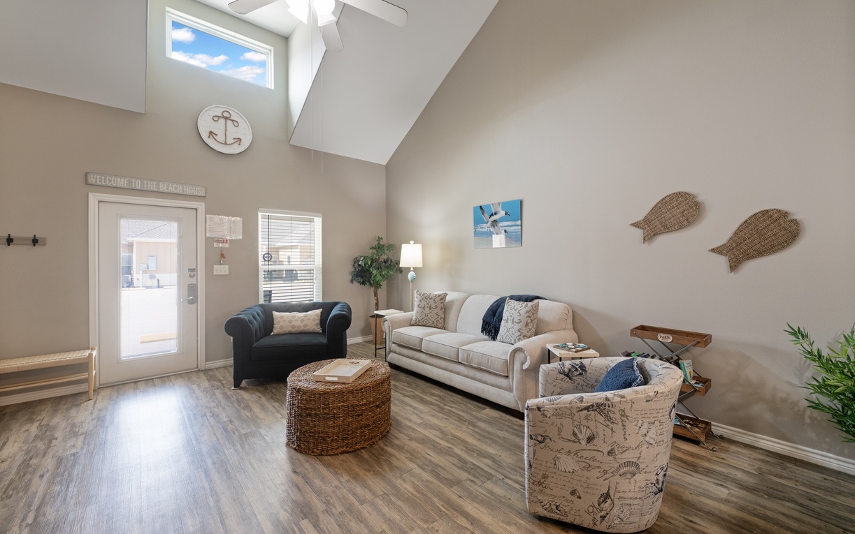 Unwind in your coastal-themed living room with vaulted ceilings, comfortable seating, and nautical touches that create the perfect beach house atmosphere.
