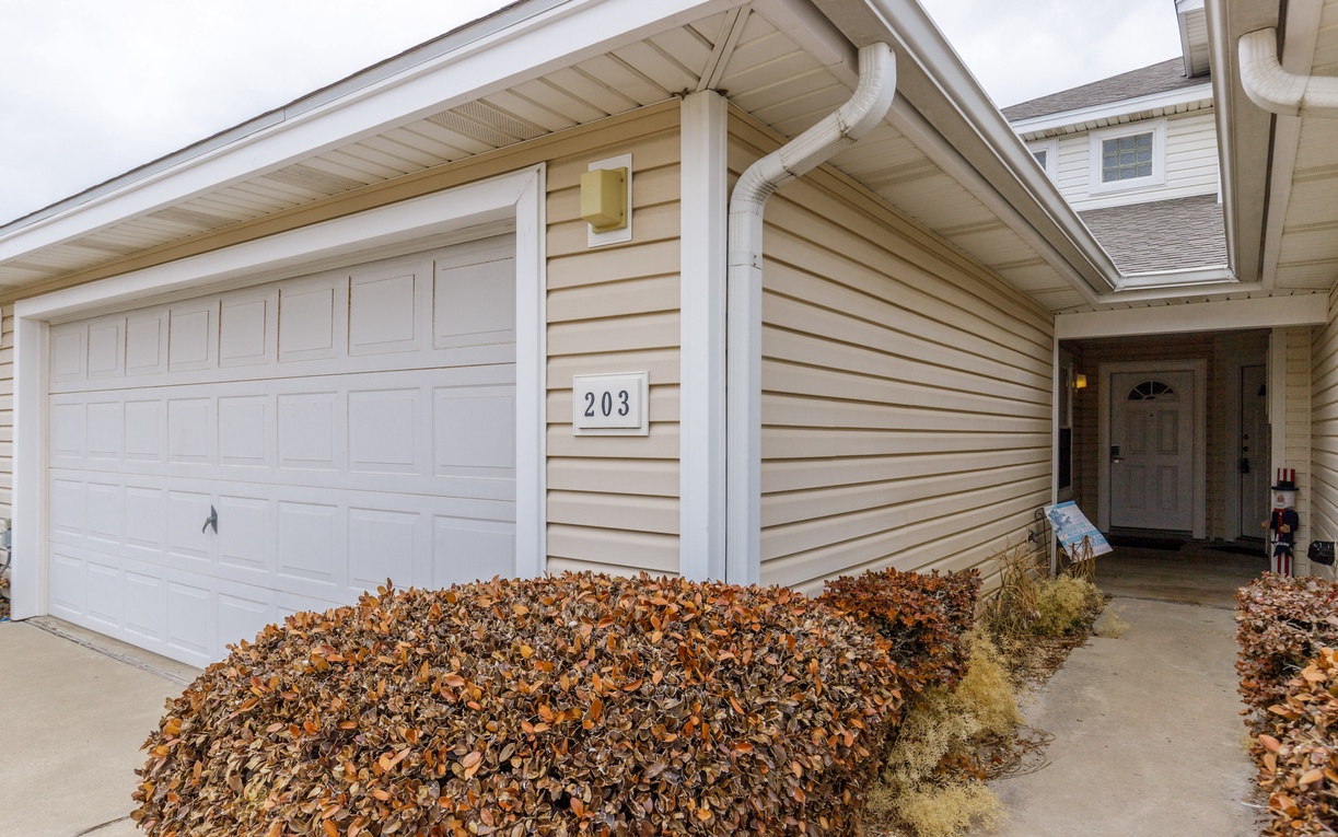 Welcoming property entrance with convenient garage parking and seasonal landscaping creates an inviting arrival experience.