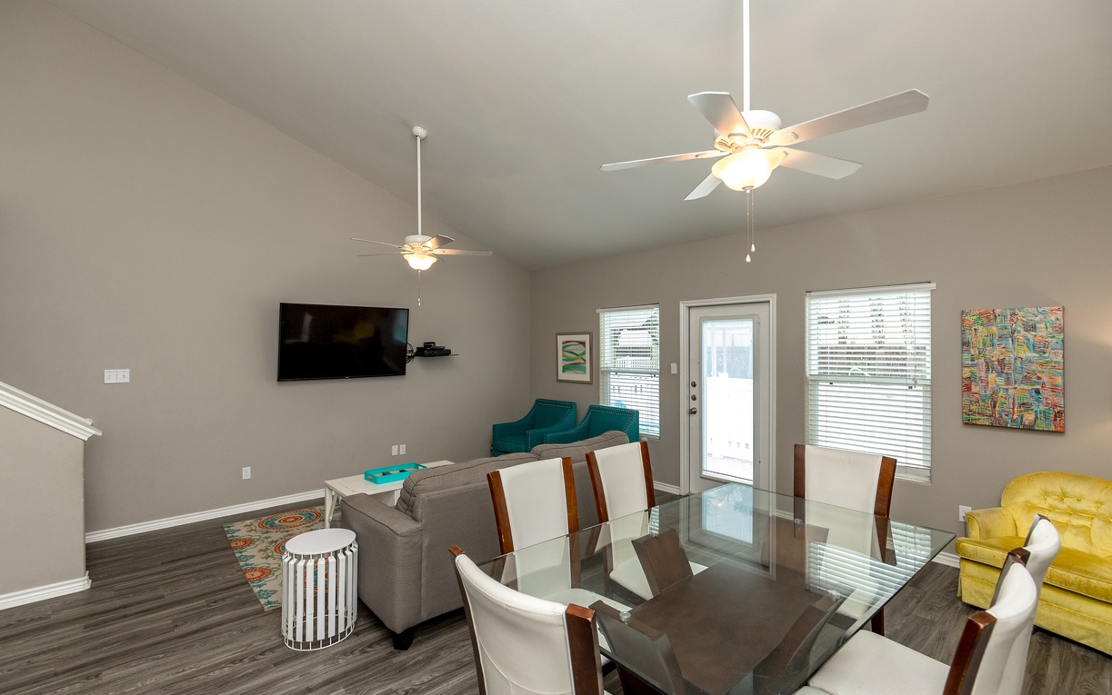 Gather around your elegant glass dining table beneath soft ceiling fans, perfect for memorable meals and conversations in this bright, welcoming space.