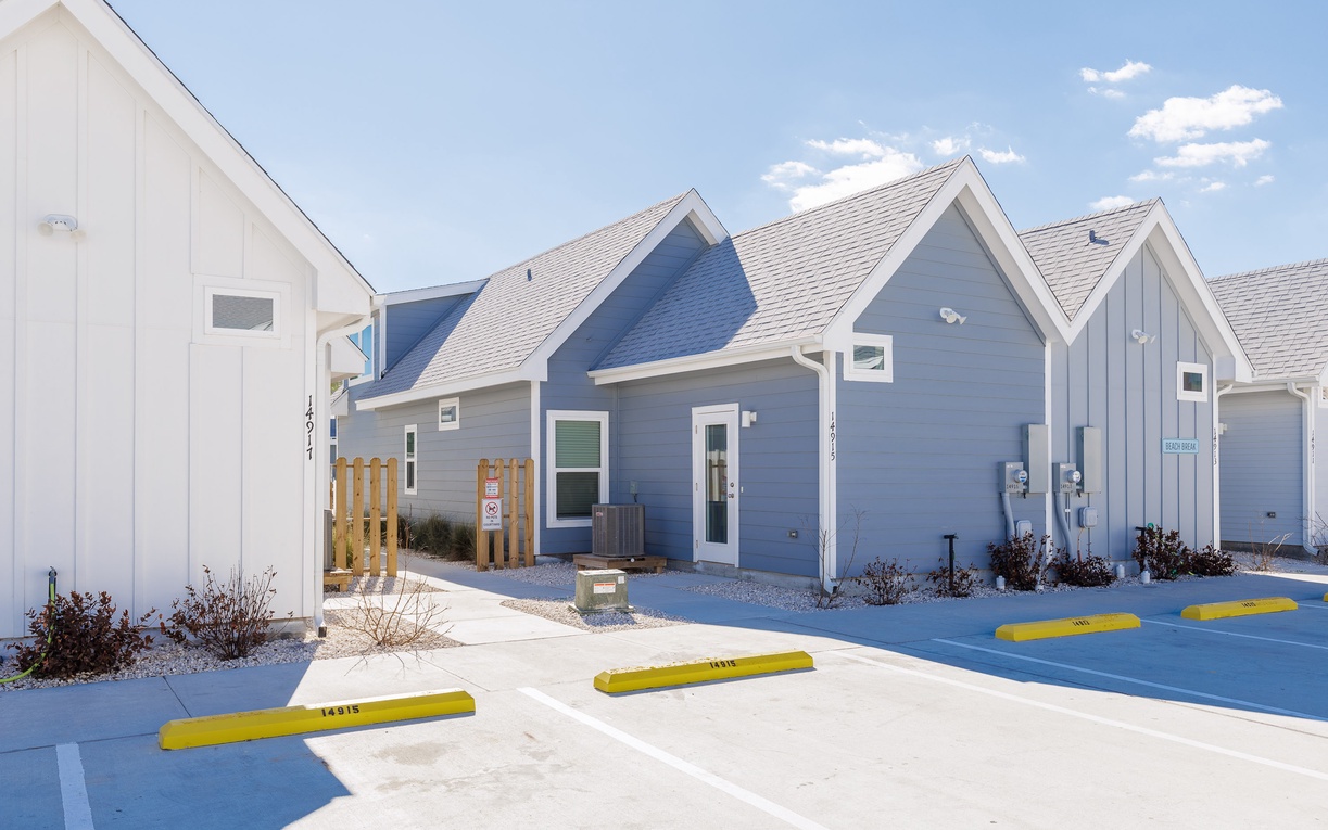 Charming blue and white cottages create a welcoming coastal village atmosphere with convenient parking right at your doorstep.