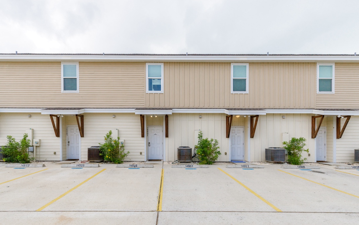 Modern townhome-style building with numbered parking spaces and AC units for each unit.