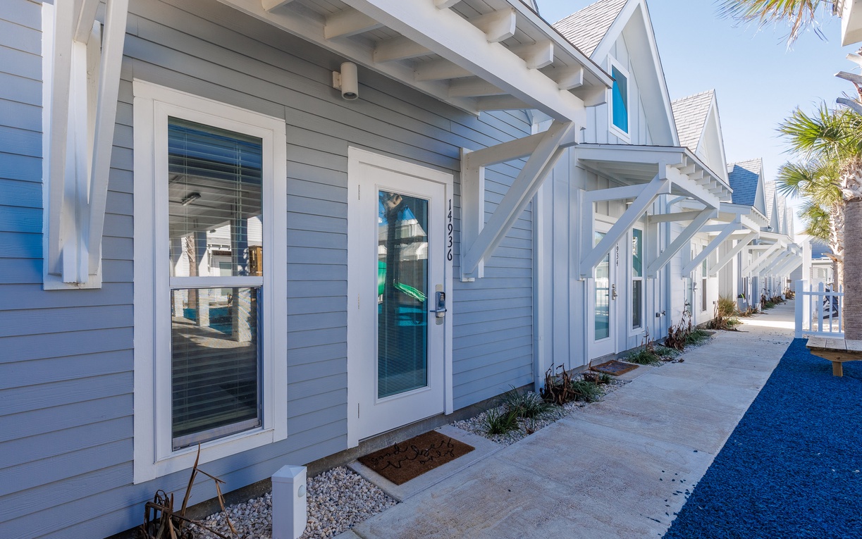 Charming coastal-style building with fresh blue siding and white trim, nestled among palm trees in a sunny beachside setting.