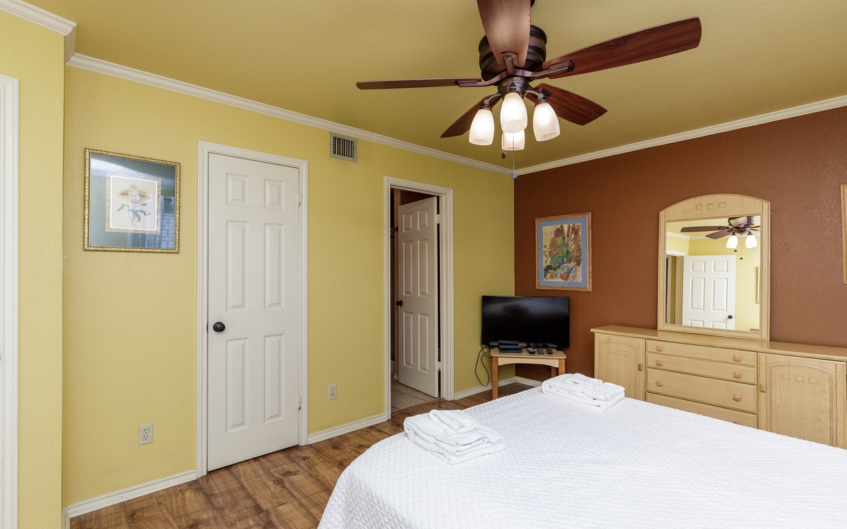 Unwind in your colorful bedroom featuring a ceiling fan, flat-screen TV, and convenient storage for your belongings.