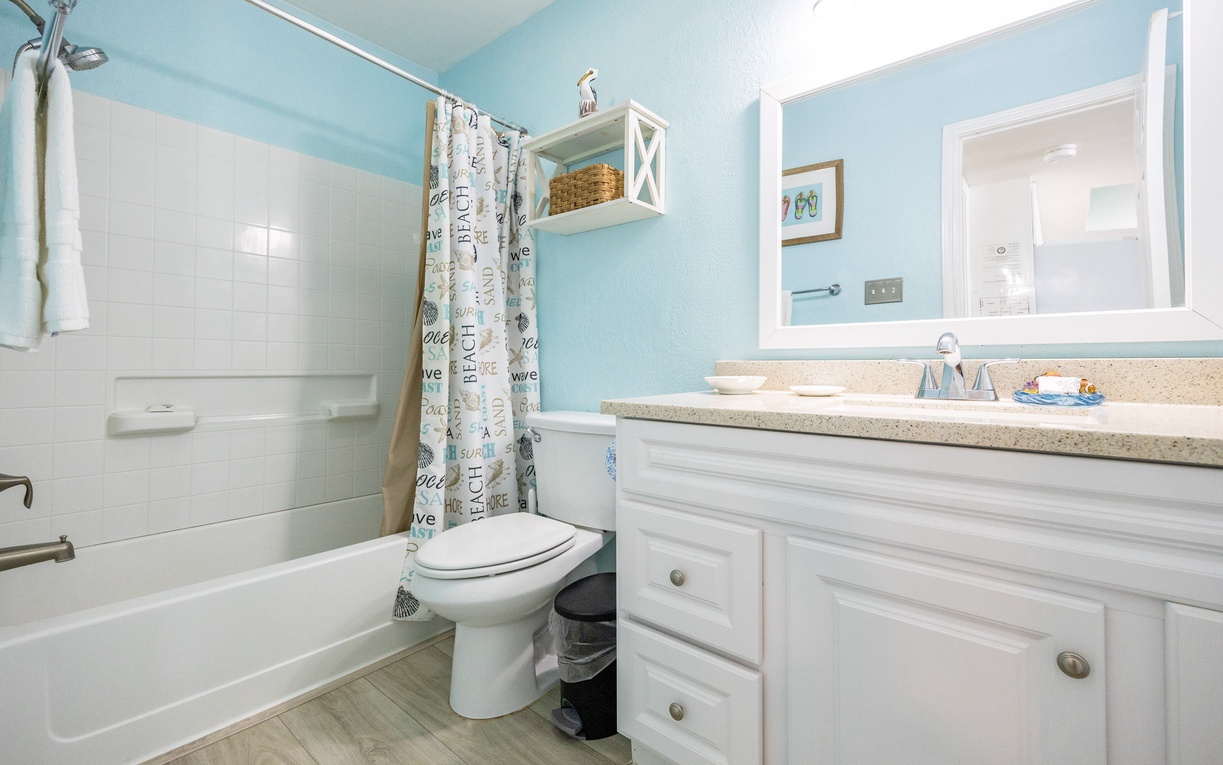 Refresh in your bright coastal bathroom featuring a soothing tub-shower combo and cheerful beach-themed decor.
