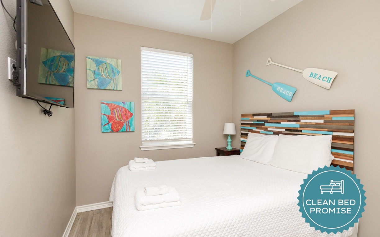 Your cozy coastal bedroom features a unique striped headboard and cheerful beach artwork to help you drift off peacefully.