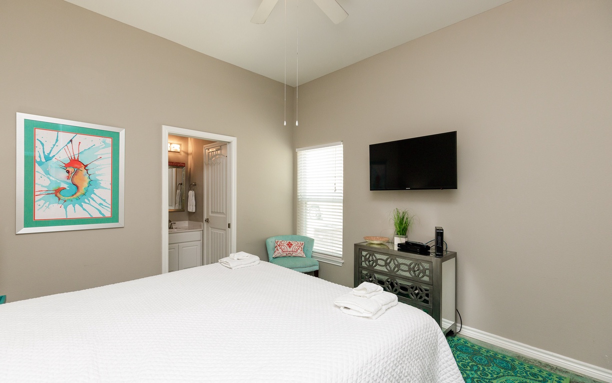 Your peaceful bedroom retreat features a plush bed, vibrant artwork, and modern amenities for the perfect night's rest.