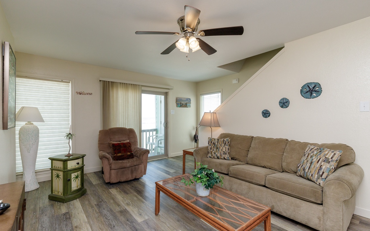 Sink into plush seating with ocean-themed decor while the ceiling fan keeps you cool in this bright, welcoming living space.