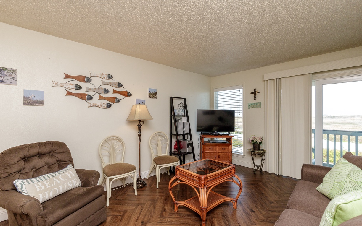 Relax in your cozy living room with coastal decor and a TV for entertainment after your beach adventures.