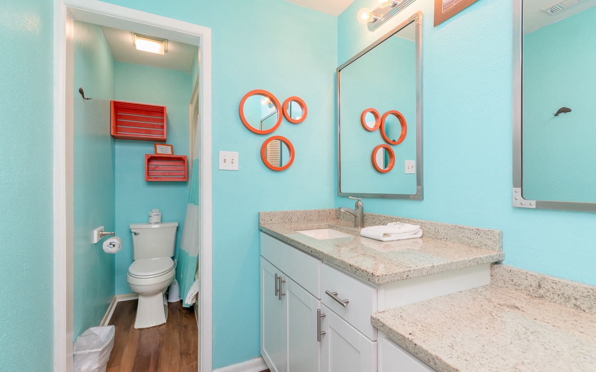 Fresh up in your vibrant bathroom featuring playful turquoise walls, granite counters, and modern fixtures that bring coastal charm to your daily routine.
